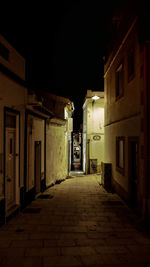 Walkway amidst illuminated buildings at night