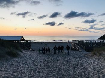 People on beach against sky during sunset