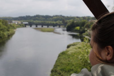 Rear view of girl looking at river against sky