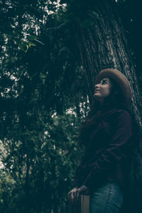 Woman standing by tree in forest