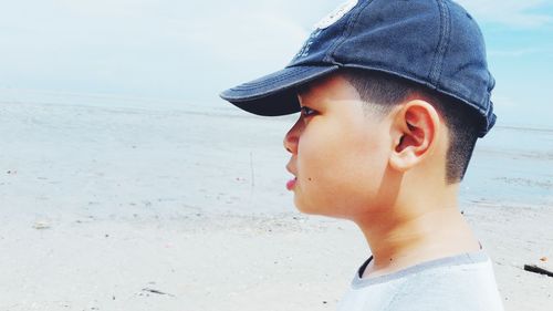Side view of boy wearing cap at beach