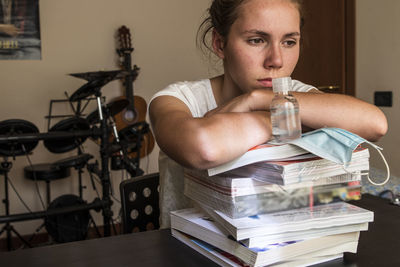 Young female student prepares to back to school with books and covid prevention devices