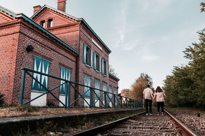 Rear view of people walking on building against sky