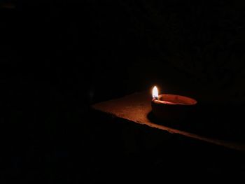 Close-up of lit candle in darkroom