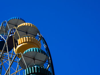 Low angle view of ferris wheel against clear blue sky