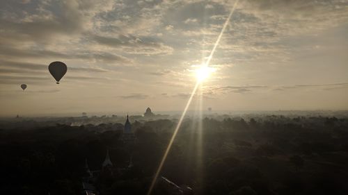 Silhouette hot air balloon flying over landscape against sky during sunset