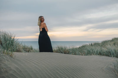 Woman standing on beach against sky