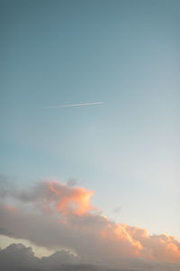 Low angle view of vapor trail in sky during sunset