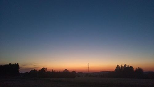 Silhouette trees on field against clear sky during sunset