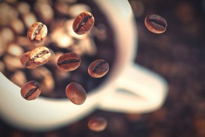 Close-up of coffee beans with coffee cup on table