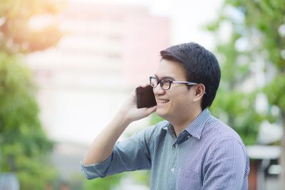 Smiling man looking away while talking on phone outdoors