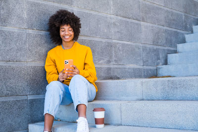 Woman using phone while sitting on staircase