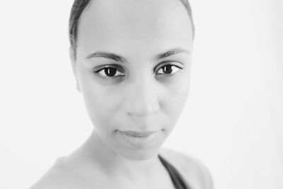 Close-up portrait of smiling young woman against white background