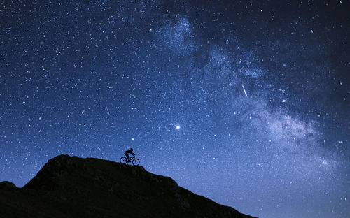 Low angle view of silhouette mountain against sky at night