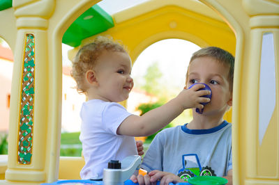 Cute girl feeding brother while playing outdoors