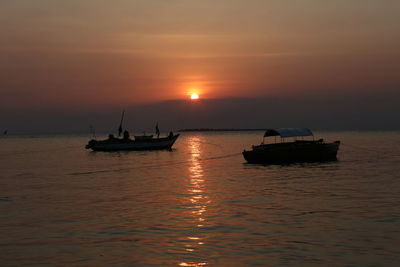 Boat sailing in sea against sky during sunset