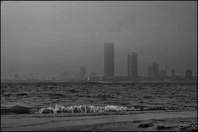 Scenic view of sea and buildings against clear sky