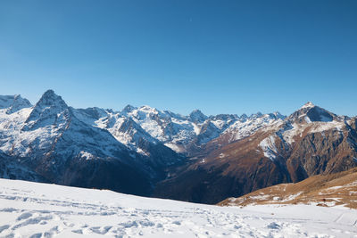 Scenic view of snow covered mountains against clear blue sky
