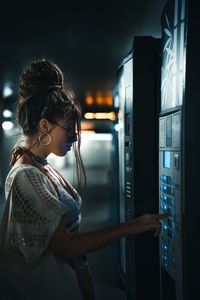 Side view of woman standing at illuminated home