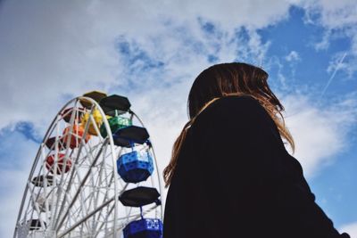 Low angle view of woman and ferris wheel against sky