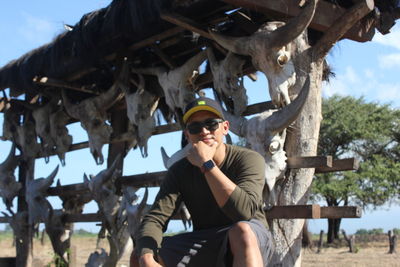 Full length of young man sitting on sunglasses