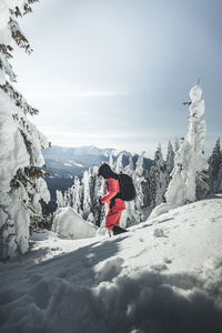 Man hiking on snowcapped mountain against sky