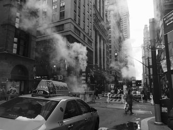 Smoke emitting from chimneys on street in city