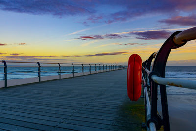 Life belt on pier over sea against sky