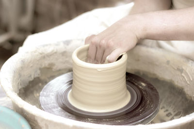 Cropped hands of person molding shape on pottery wheel