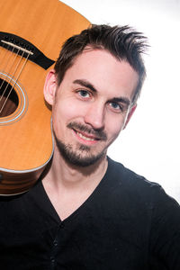 Close-up portrait of man holding guitar against white background