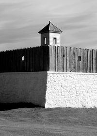 House on beach by building against sky