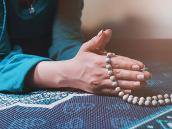 Midsection of woman praying on carpet at home