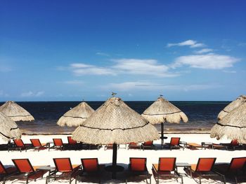 Sun loungers with canopies in row against calm sea