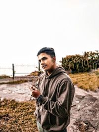 Young man standing on land against clear sky