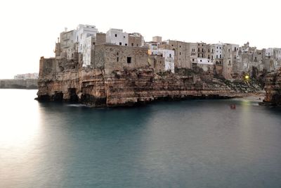 Buildings by sea against sky