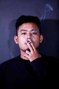 Close-up of man smoking cigarette against gray background