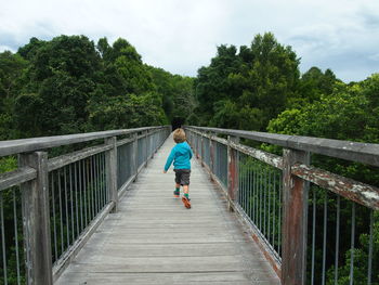 Rear view of man walking on footbridge