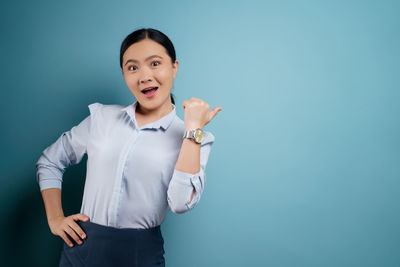 Portrait of a smiling young woman against blue background