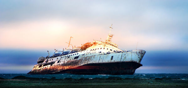 Abandoned boat in sea against sky