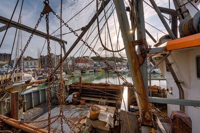 Sailboats moored at harbor against sky