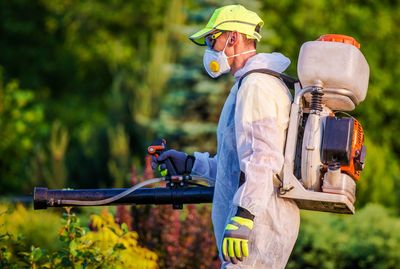 Side view of farm worker spraying pesticide
