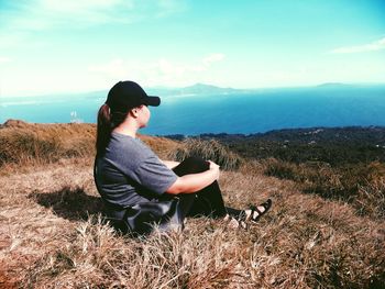 Full length of woman looking at sea from mountain peak against sky