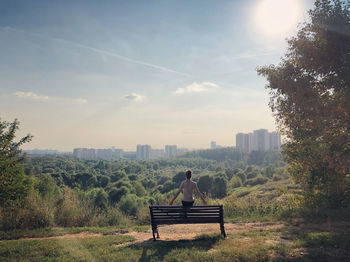 Rear view of man sitting on bench in park