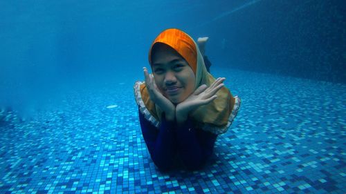 Portrait of teenage girl with hands on chin in swimming pool