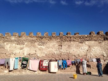 Woman drying laundry against old wall