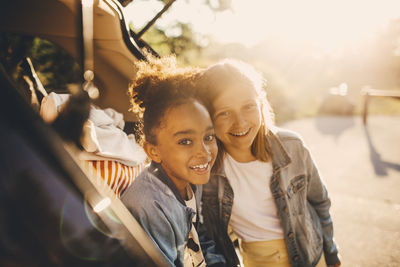 Portrait of smiling multi-ethnic girls in car trunk during picnic