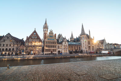 Buildings by river against clear sky