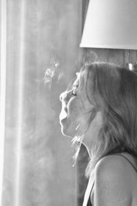 Side view of woman smoking at home