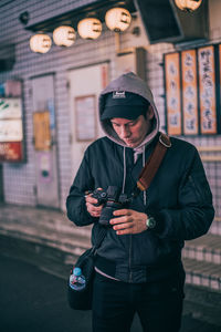 Young man using smart phone while standing outdoors