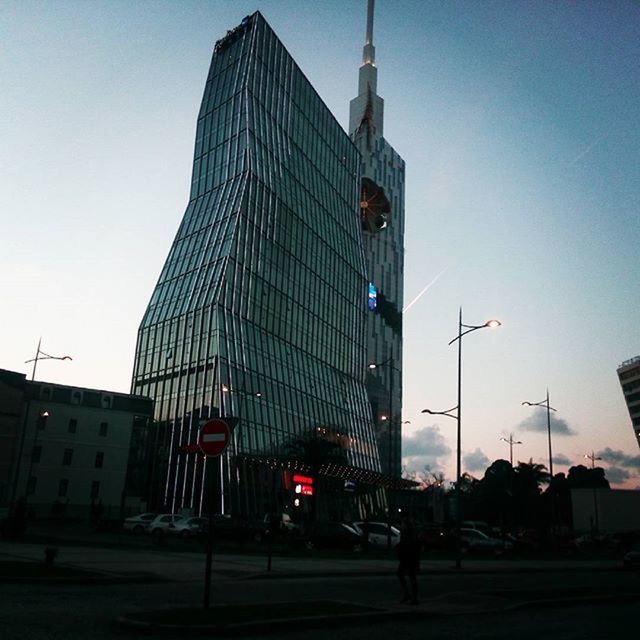 building exterior, architecture, built structure, clear sky, city, low angle view, tower, street, tall - high, sky, street light, transportation, car, development, building, outdoors, skyscraper, road, sunlight, no people